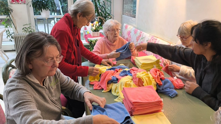 Senioren beim gemeinsamen Falten von bunten Handtüchern in einer Einrichtung Senioren falten bunte Handtücher in einer Gemeinschaftseinrichtung