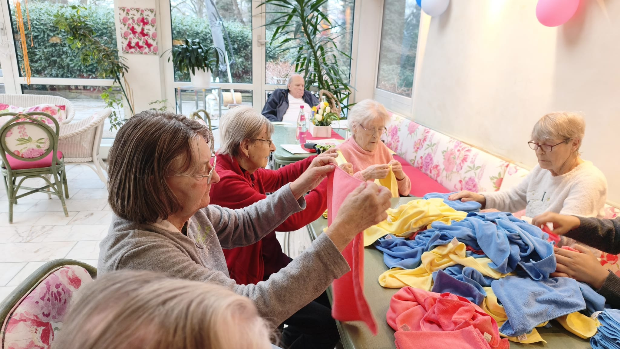 Senioren beim gemeinsamen Basteln mit bunten Tüchern in einer gemütlichen Umgebung