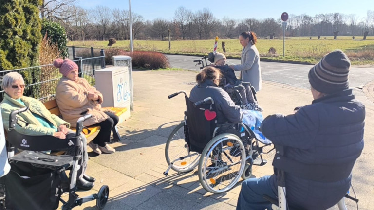 Gruppe von Senioren im Rollstuhl und auf einer Bank an einem sonnigen Tag im Freien