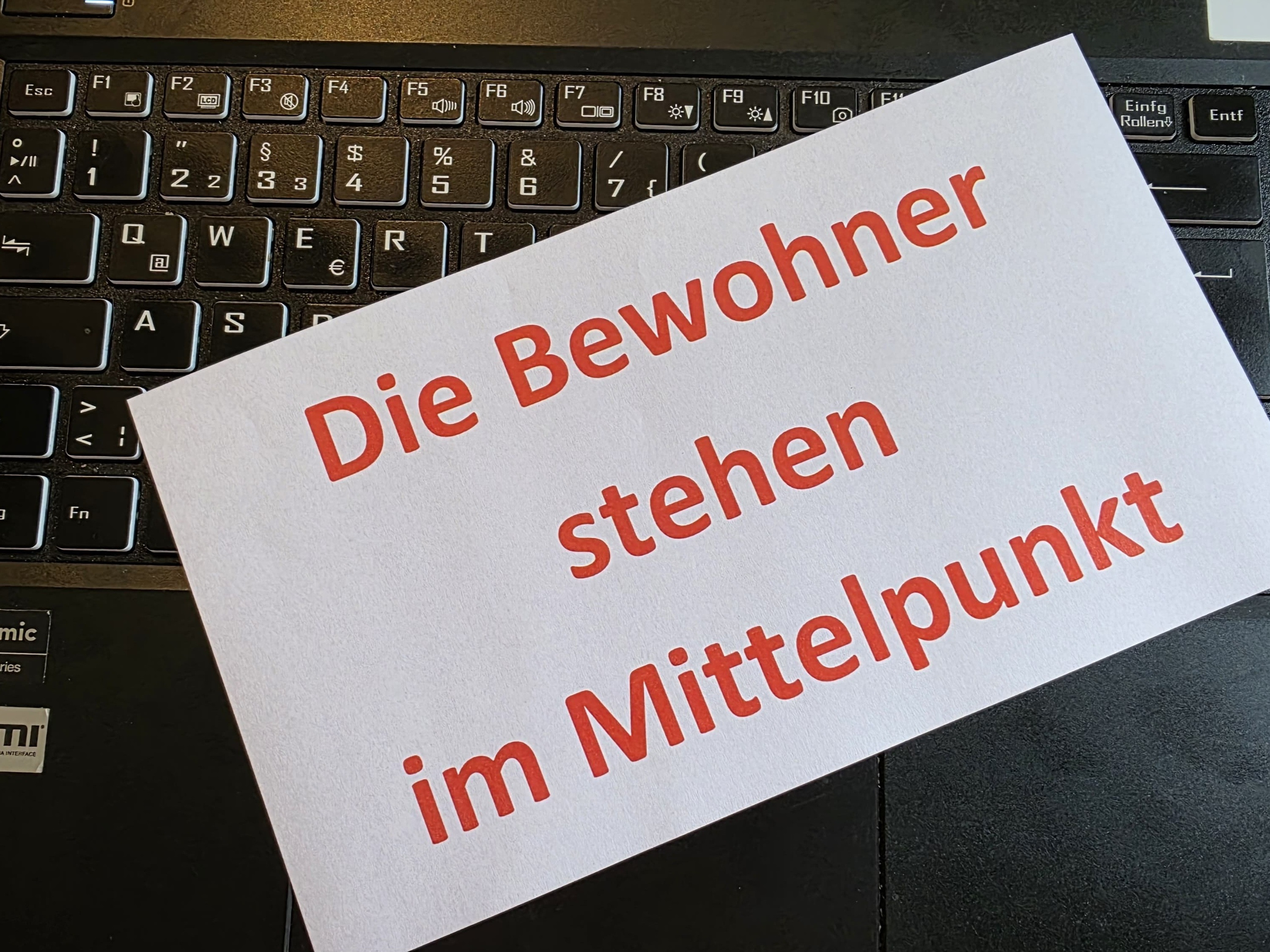 Papier mit Aufschrift 'Die Bewohner stehen im Mittelpunkt' auf einer Tastatur