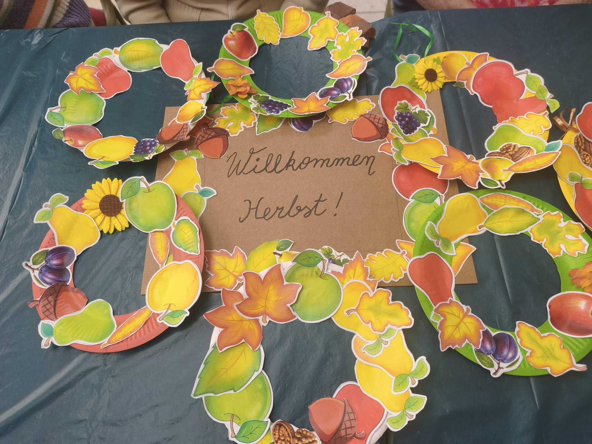 Bastelarbeiten mit herbstlichen Motiven und Schriftzug 'Willkommen Herbst' auf einem Tisch