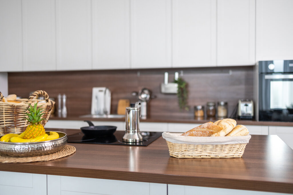 Materialmix in der Kfcche nach Kfcchenmodernisierung – moderne Kfcche mit Holzarbeitsplatte und Brotkorb Materialmix in der Kfcche nach Kfcchenmodernisierung mit Holzarbeitsplatte, modernen Gere4ten und Brotkorb auf der Theke
