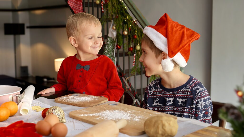 Kinder bereiten Teig für die Kuchenmodernisierung in der Adventszeit vor, mit weihnachtlicher Dekoration im Hintergrund.