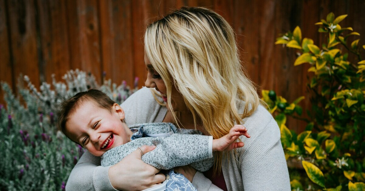 Glückliche Mutter mit lachendem Sohn Mutter hält lachenden Sohn im Arm