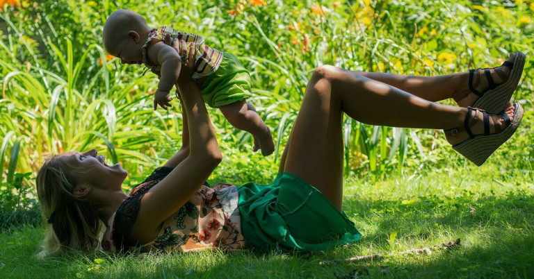 Yoga mit Baby draußen – Mutter und Kind beim Yoga im Freien Frau macht Yoga mit Baby draußen im Grünen