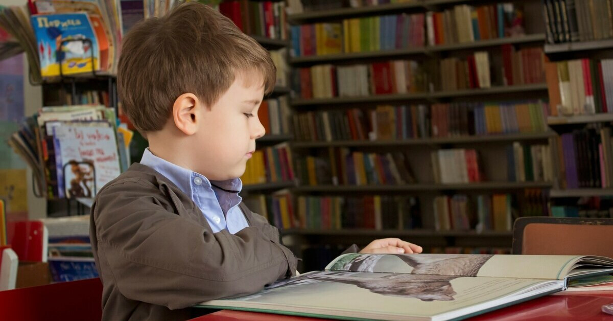 Schulkind liest ein Buch in einer Bibliothek