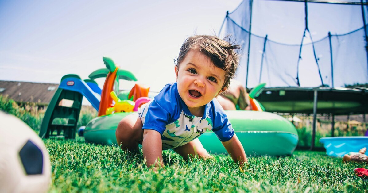 Kleinkind spielt auf dem Spielplatz im Sommer auf dem Rasen