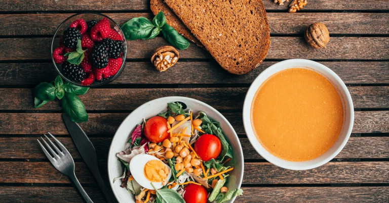 Obst und Gemüse – gesunde Mahlzeit mit Vollkornbrot, Salat, Beeren und Suppe Obst und Gemüse auf einem Holztisch mit Vollkornbrot, Salat, Beeren und Suppe