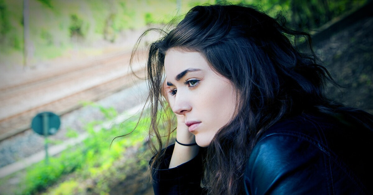 Besorgte Frau mit langen dunklen Haaren im Freien