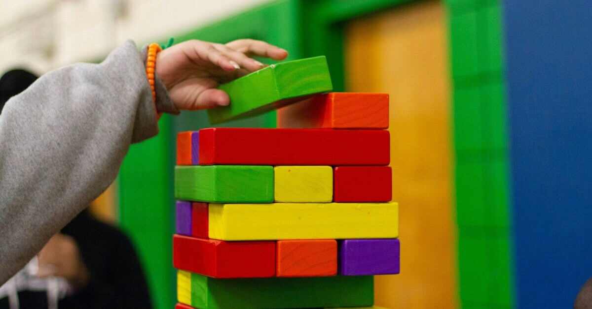 Bunte Bauklötze werden von einer Kinderhand gestapelt