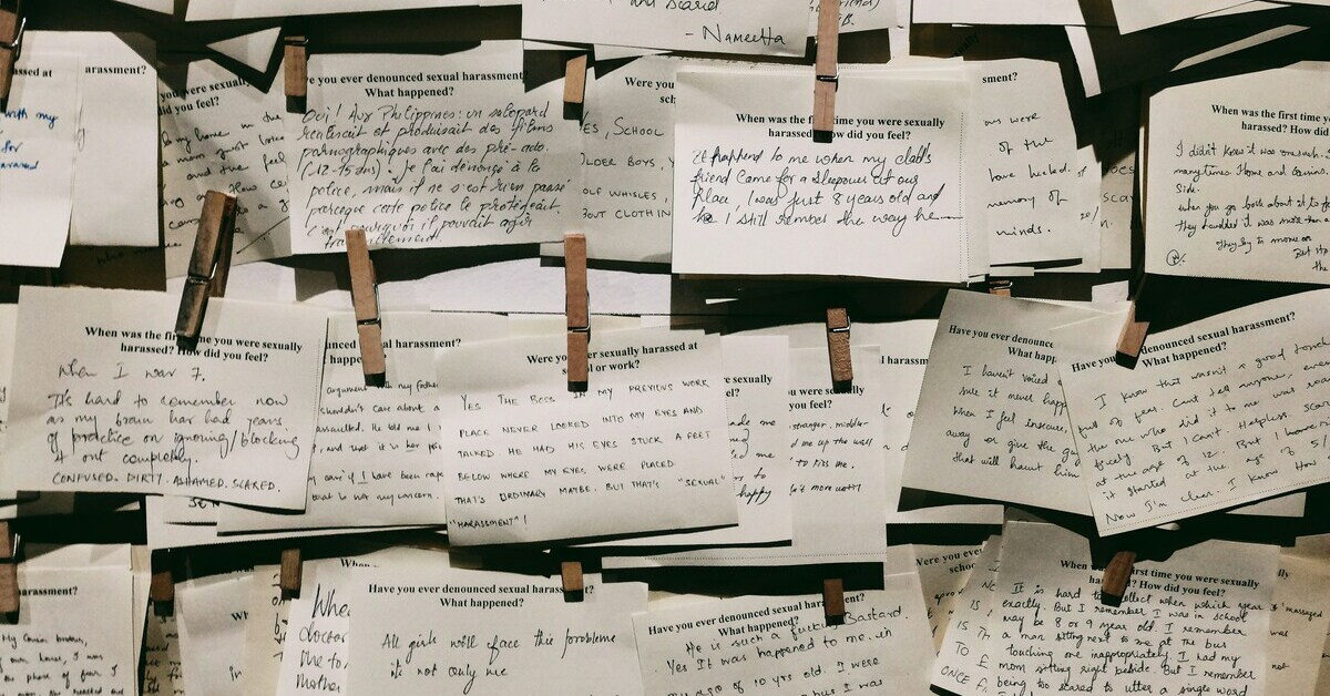 Viele übereinander hängende Zettel mit handschriftlichen Notizen und Aussagen, die an einer Wand befestigt sind.