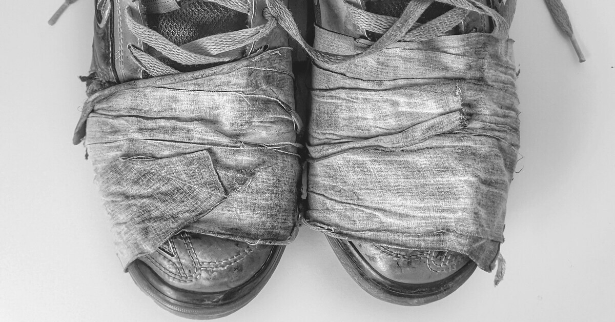 Zwei Schuhe mit Verband um die Vorderkappe, Nahaufnahme in Schwarz-weiß