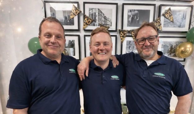 Teamfoto Dettmar – drei Mitarbeiter in blauen Poloshirts bei einer Jubiläumsfeier