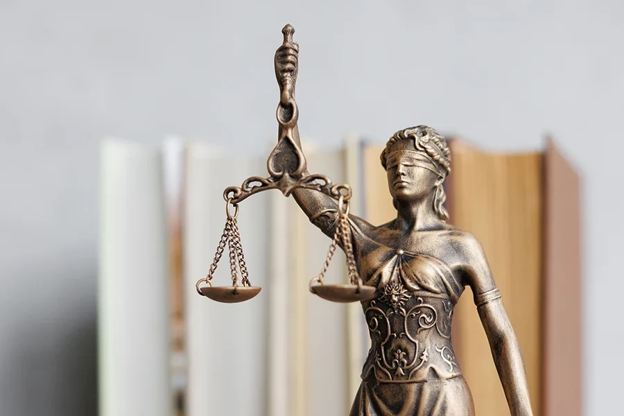 Justizia Statue mit Waage vor unscharfem Bücherregal