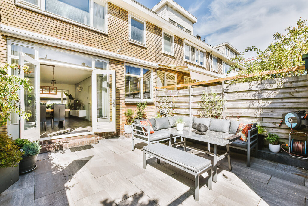 Saubere Terrasse nach Terrassenreinigung im Frühling mit moderner Sitzgruppe vor einem Reihenhaus