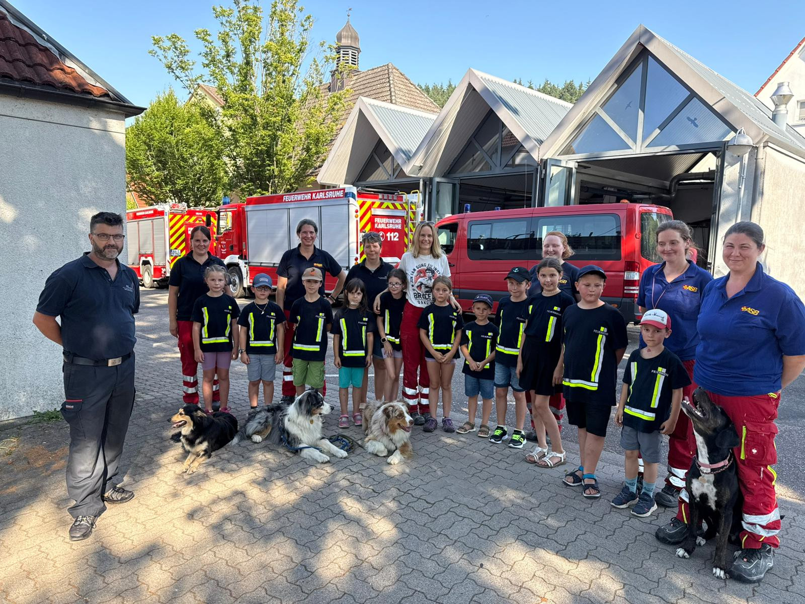 Kindergruppe mit Feuerwehr Karlsruhe und Rettungshunden vor Feuerwehrfahrzeugen Kindergruppe und Erwachsene vor Feuerwehrfahrzeugen der Feuerwehr Karlsruhe mit Rettungshunden