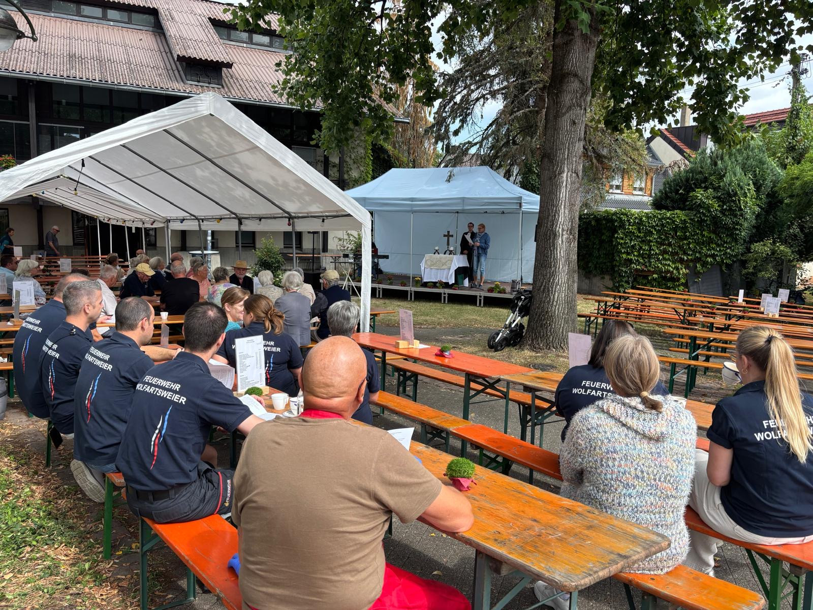 Gottesdienst im Freien mit Besuchern und Feuerwehr Wolfartsweier unter Pavillon und Zelt