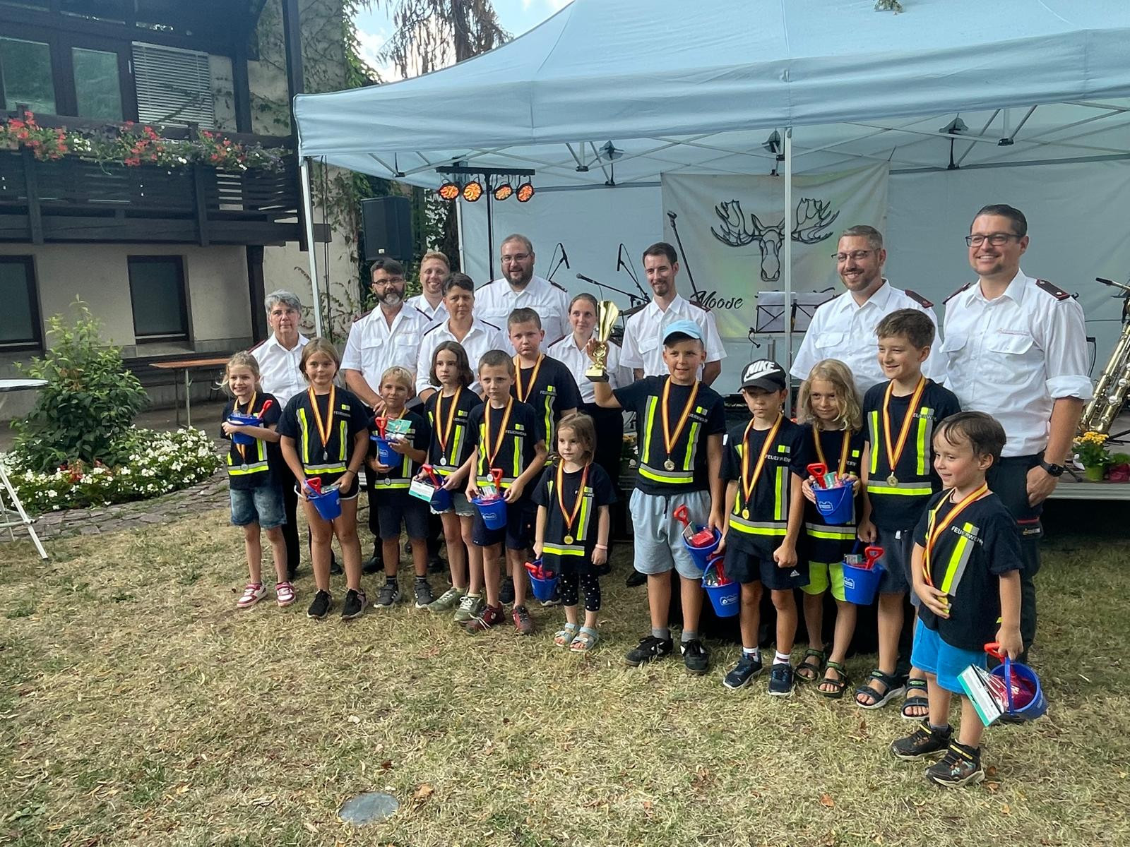 Kindergruppe mit Medaillen und Betreuern bei Feuerwehrfest Siegerehrung im Freien