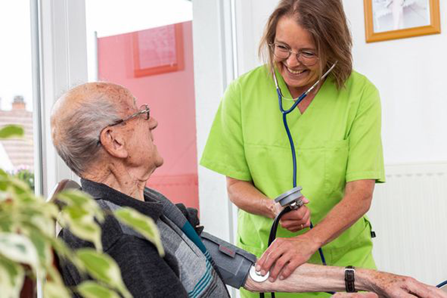 Pflegekraft misst Blutdruck bei Senior im Pflegeheim
