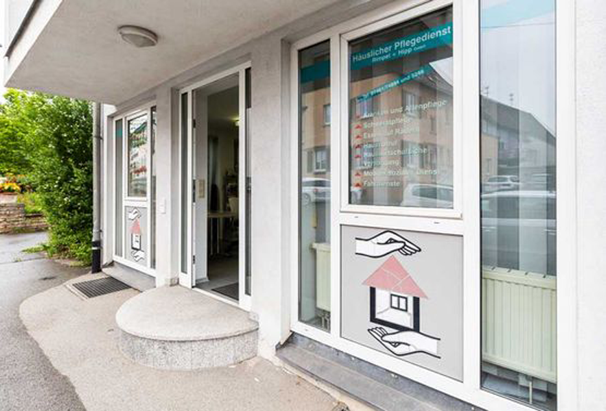 Eingang eines häuslichen Pflegedienstes mit Beschriftung und Symbol für Pflege