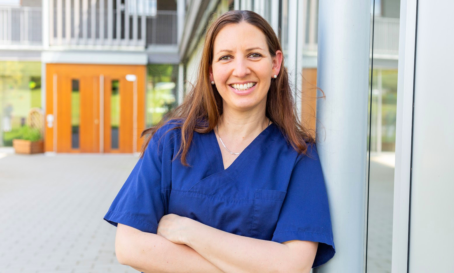 Nicole Etter in blauer Arbeitskleidung vor einem modernen Gebäude