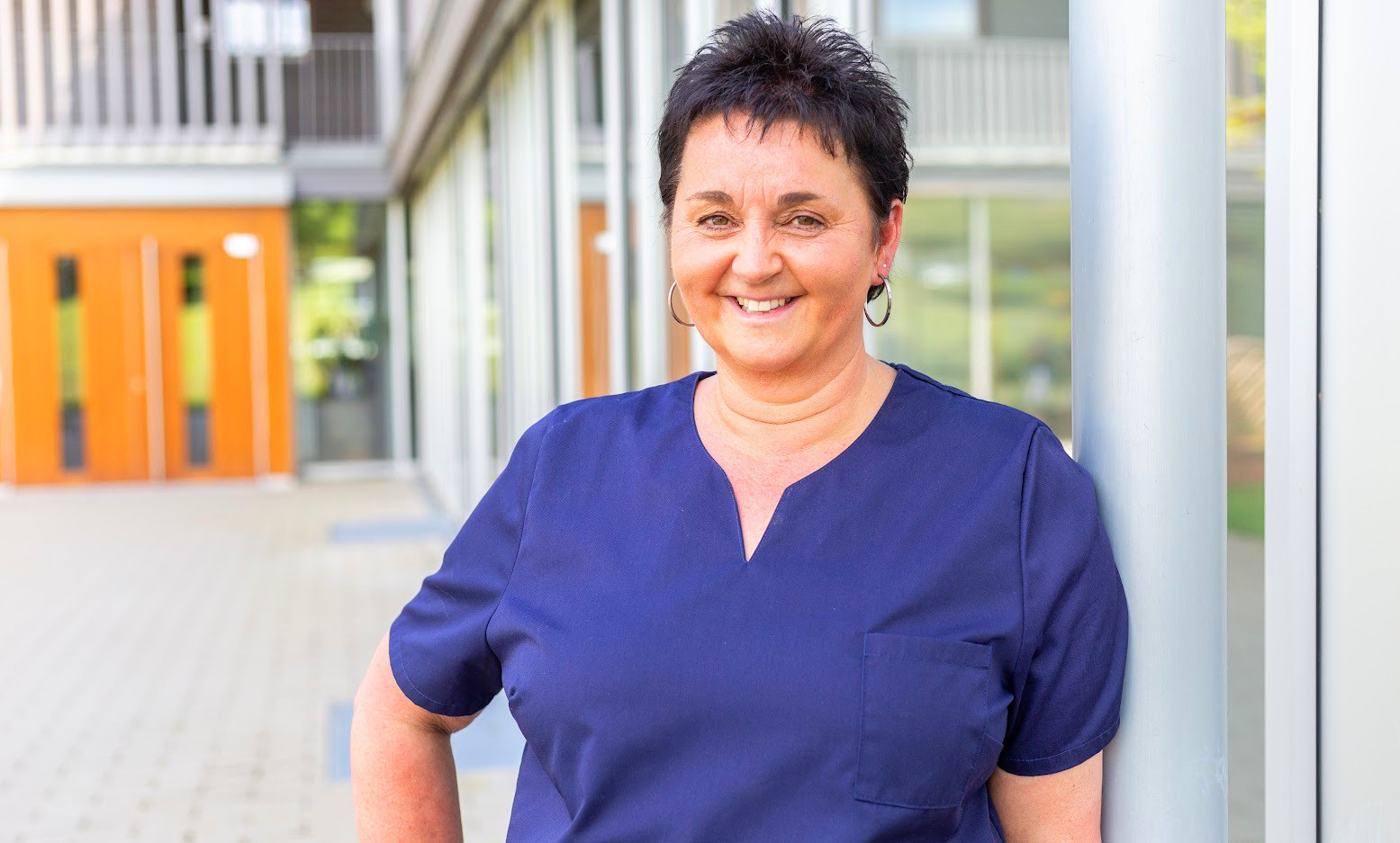 Sabine Brunnenkant im blauen Oberteil vor einem modernen Gebäude