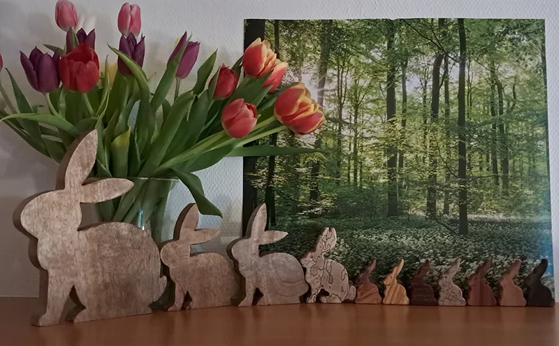 Holzhasen-Dekoration auf einer Startseite mit Tulpen und Waldbild im Hintergrund