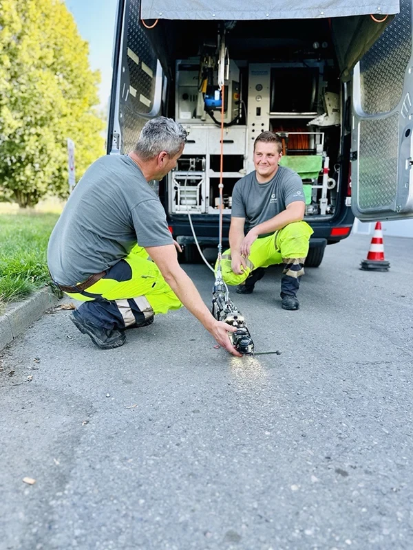 Zwei Arbeiter führen eine Kanalinspektion mit moderner Technik an einem Einsatzfahrzeug durch