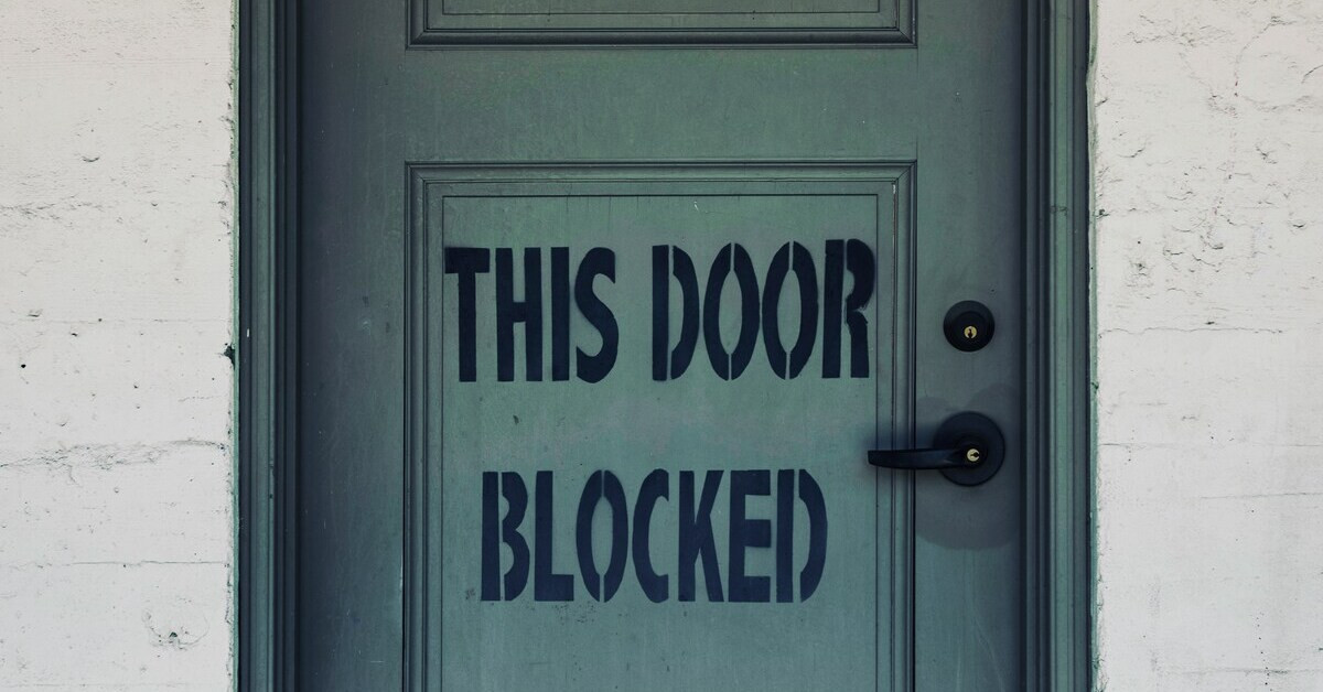 Blockierte Tür mit Aufschrift 'This door blocked' in schwarzer Schrift