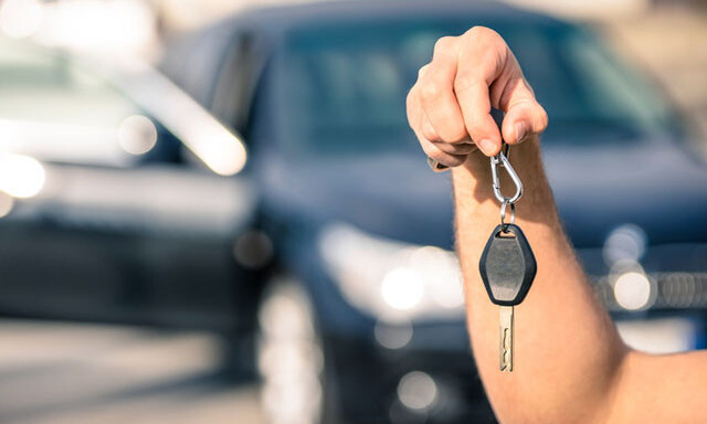 Autoöffnung: Hand hält Autoschlüssel vor Fahrzeug