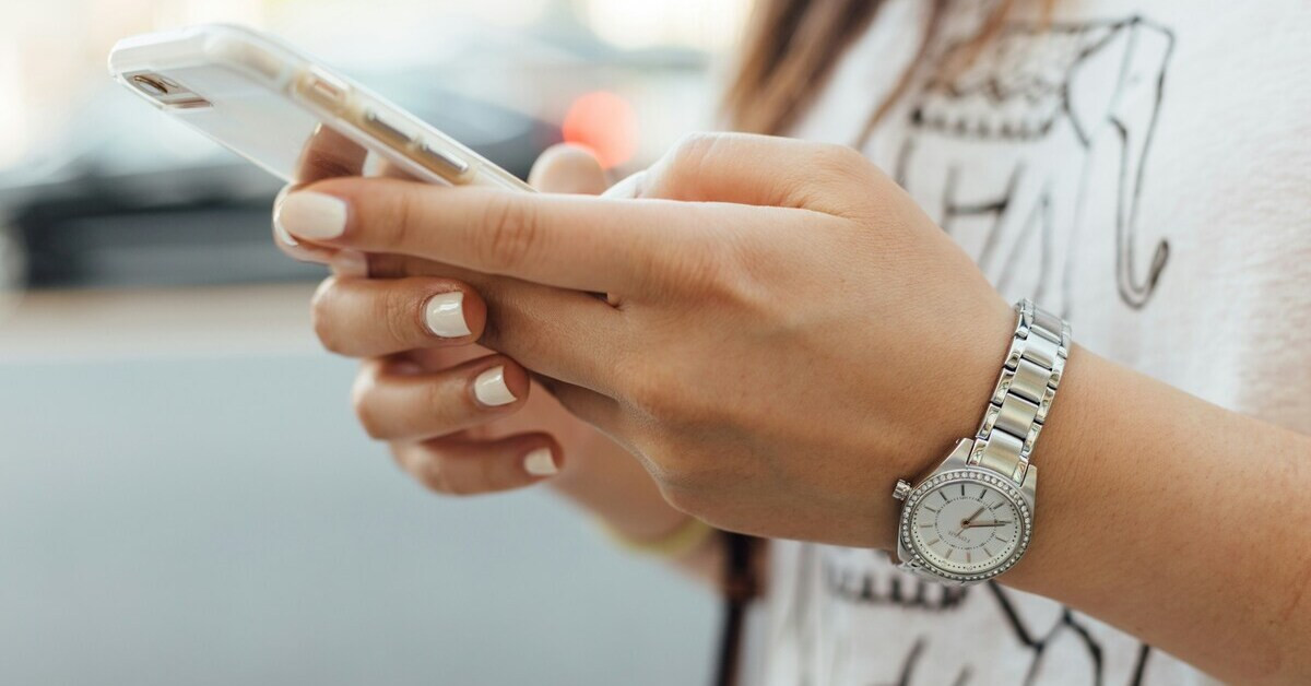 Frau hält ein Handy in der Hand und tippt eine Nachricht