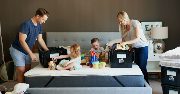 Familie packt Umzugskisten im Wohnzimmer zusammen mit Kindern und Spielzeug