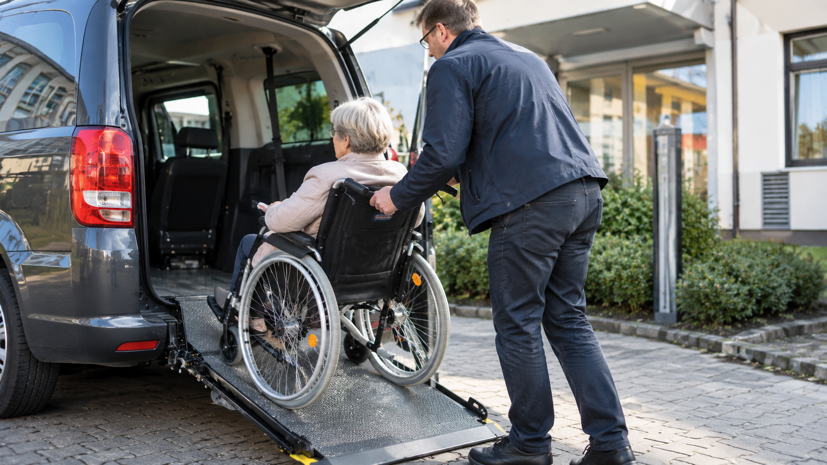 Mann hilft Seniorin im Rollstuhl in barrierefreies Fahrzeug, 30. September 2026