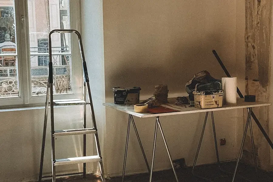 Tapezieren: Arbeitsvorbereitung mit Leiter und Tapeziertisch in heller Wohnung Tapezieren: Vorbereitung mit Leiter und Tapeziertisch am Fenster