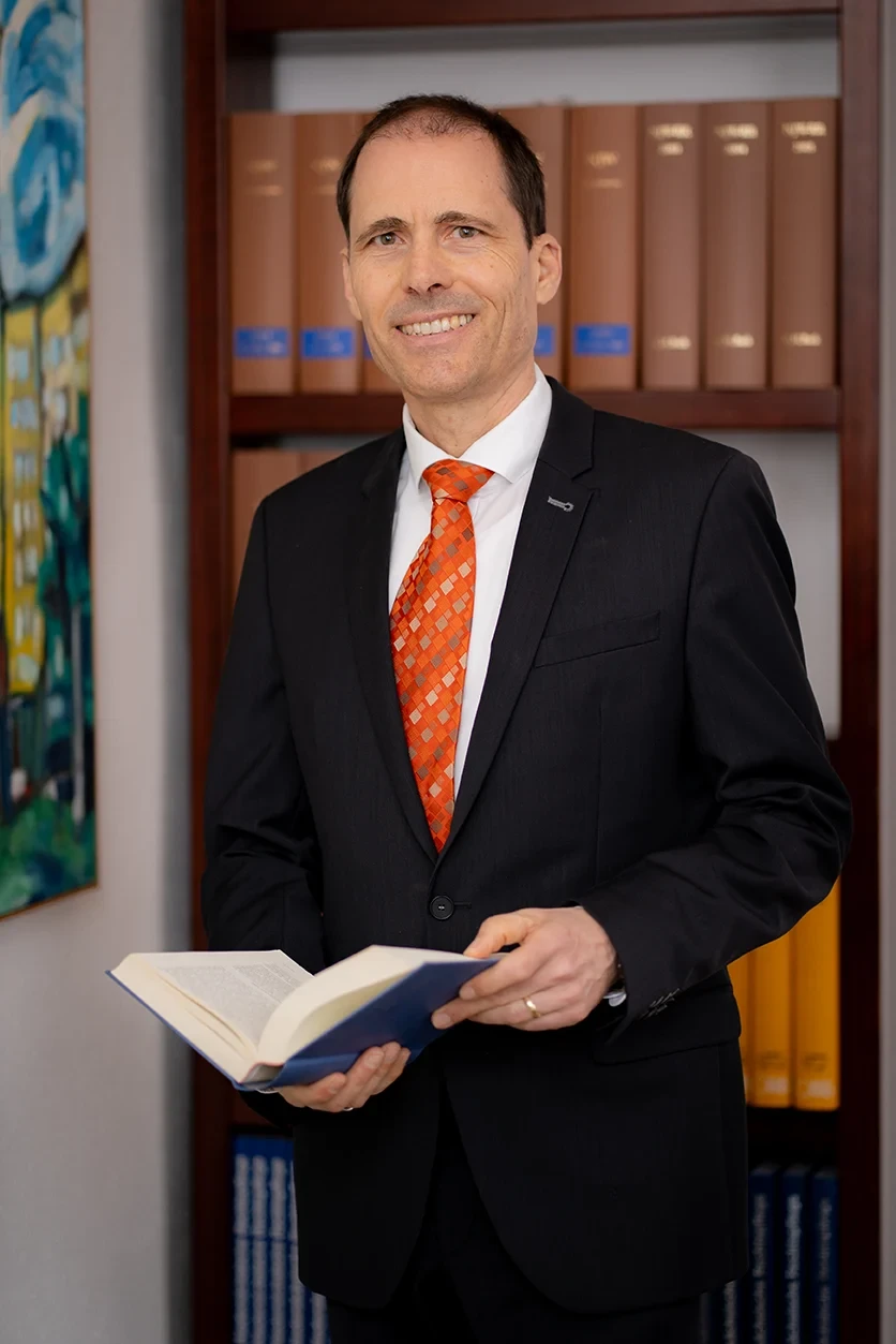 Kontakt Portrait – Geschäftsmann im Anzug mit Buch in der Hand Kontakt Portrait eines Geschäftsmanns im Anzug mit Buch in der Hand vor Bücherregal