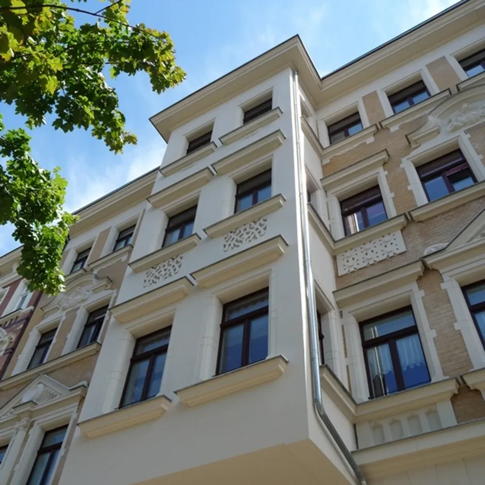 Stuckfassade und moderne Fenster, fotografiert aus der Froschperspektive bei blauem Himmel
