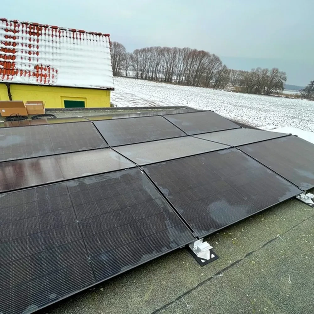 Solaranlage auf Flachdach im Winter mit verschneitem Haus im Hintergrund