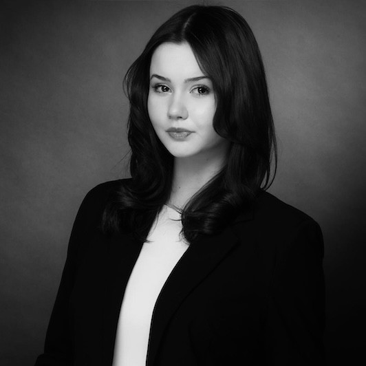 Schwarz-weiß Porträtfoto einer Frau im Business-Outfit vor neutralem Hintergrund