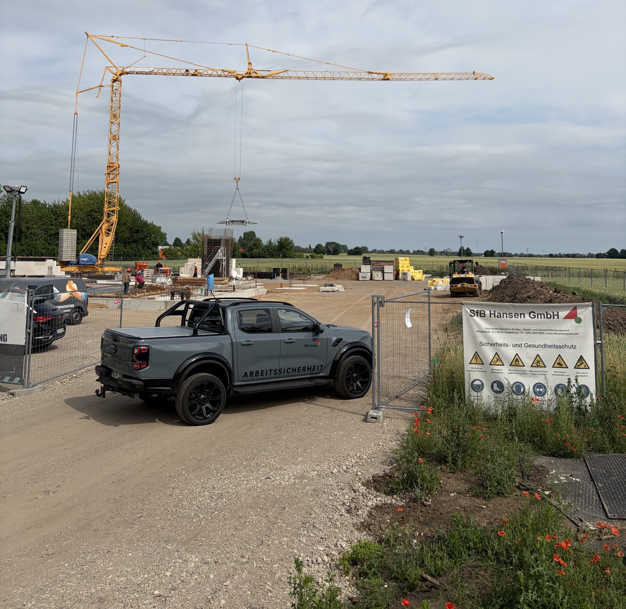 Baustelle des Neubaus der Rettungswache Olvenstedt mit Kran, Sicherheitsfahrzeug und Hinweisschild der SIB Hansen GmbH