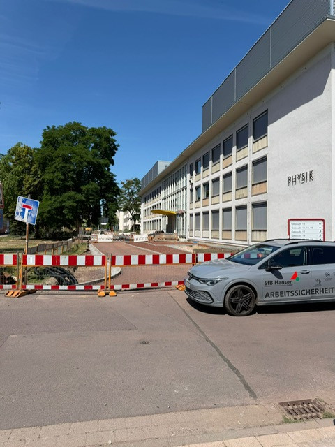 Leitungssanierung und Campusgestaltung an der Otto-von-Guericke-Universität Magdeburg, Baustelle vor dem Physikgebäude mit Absperrung und Sicherheitsfahrzeug