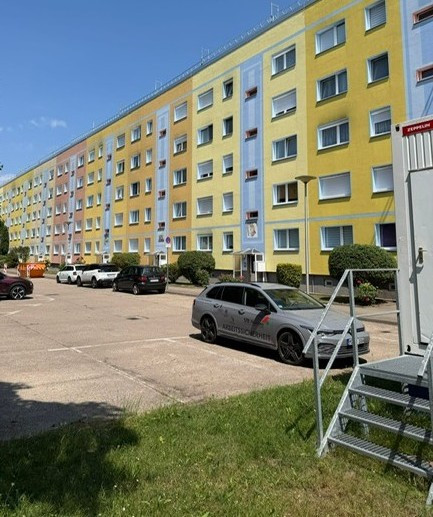 Dachsanierung eines Mehrfamilienhauses am Unterhorstweg, gelbes Wohngebäude mit Gerüst und geparkten Autos