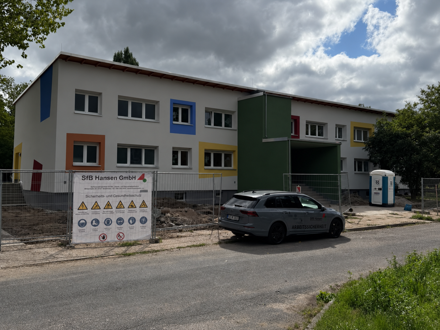 Neubau der Kita Bussi Bär mit bunter Fassade und Sicherheitsfahrzeug vor dem Gebäude