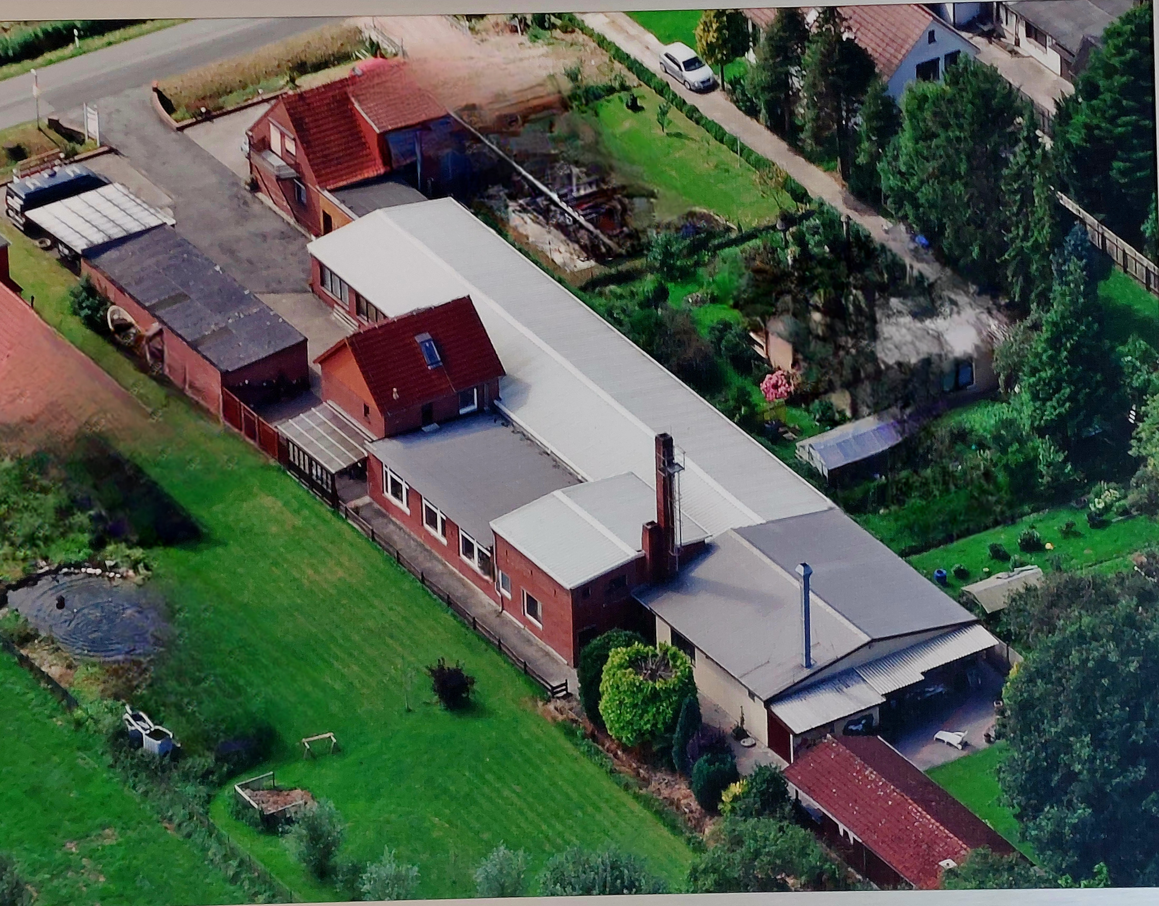 Luftaufnahme eines landwirtschaftlichen Betriebs mit mehreren Gebäuden und Grünflächen