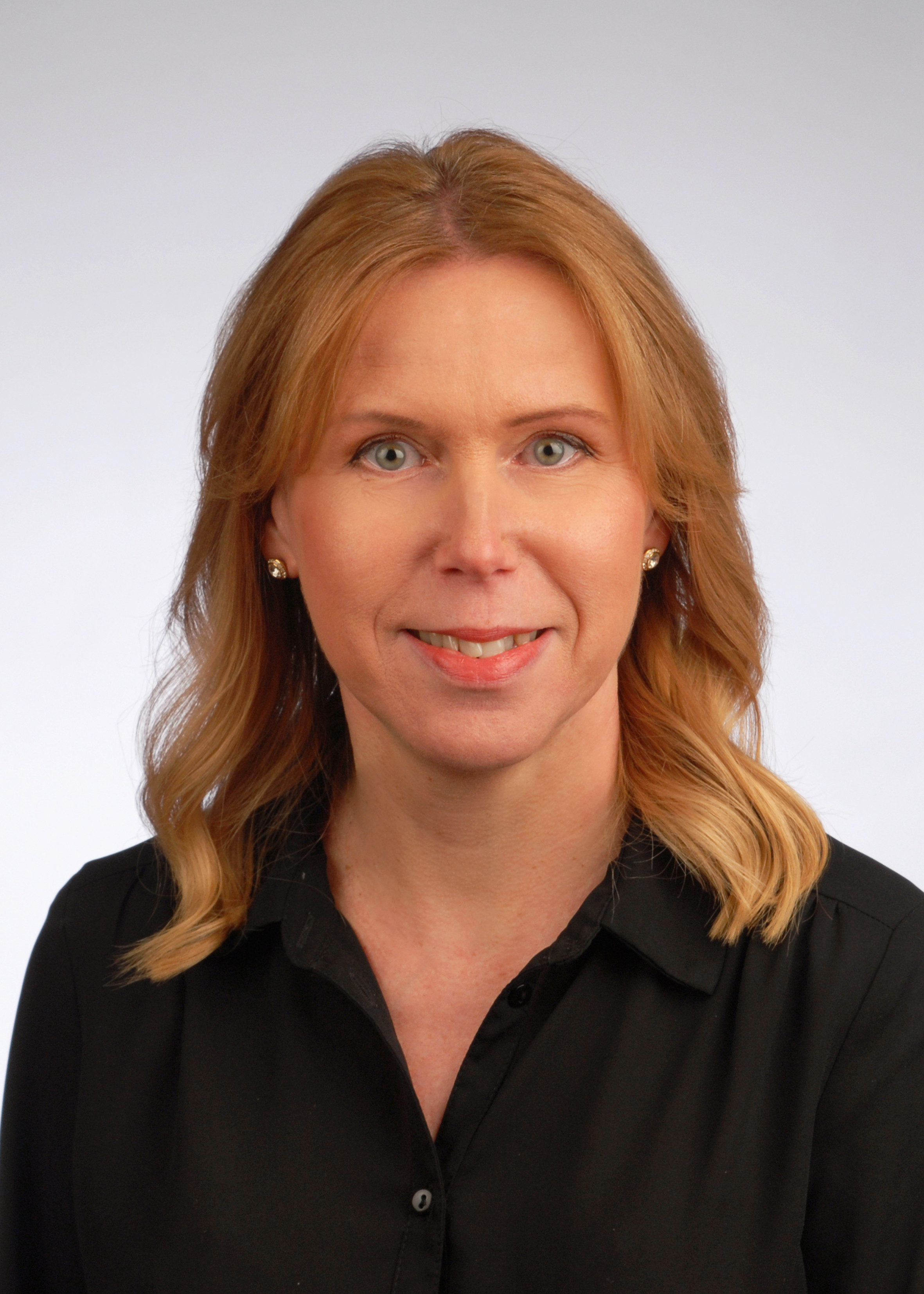 Renate Tomczak mit blonden Haaren und schwarzer Bluse vor neutralem Hintergrund