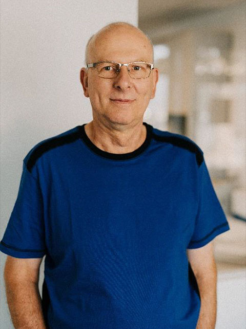 Bernd Saeger in blauem T-Shirt steht in einem Innenraum