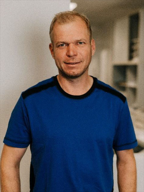 Christian Tiemann in blauem T-Shirt vor unscharfem Hintergrund