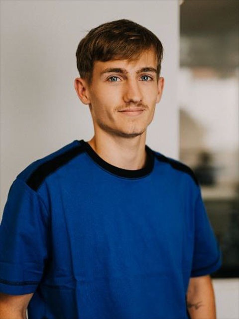 Max Schmid in blauem T-Shirt vor unscharfem Hintergrund