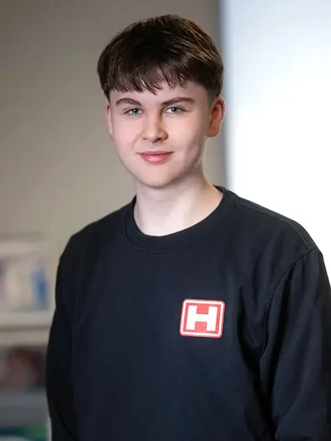 Tim Bensiek mit schwarzem Pullover und rotem H-Logo