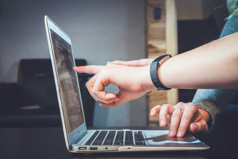 Personen arbeiten an einem Laptop, um einen Beitrag zur Relevanz von Social Media zu schreiben.