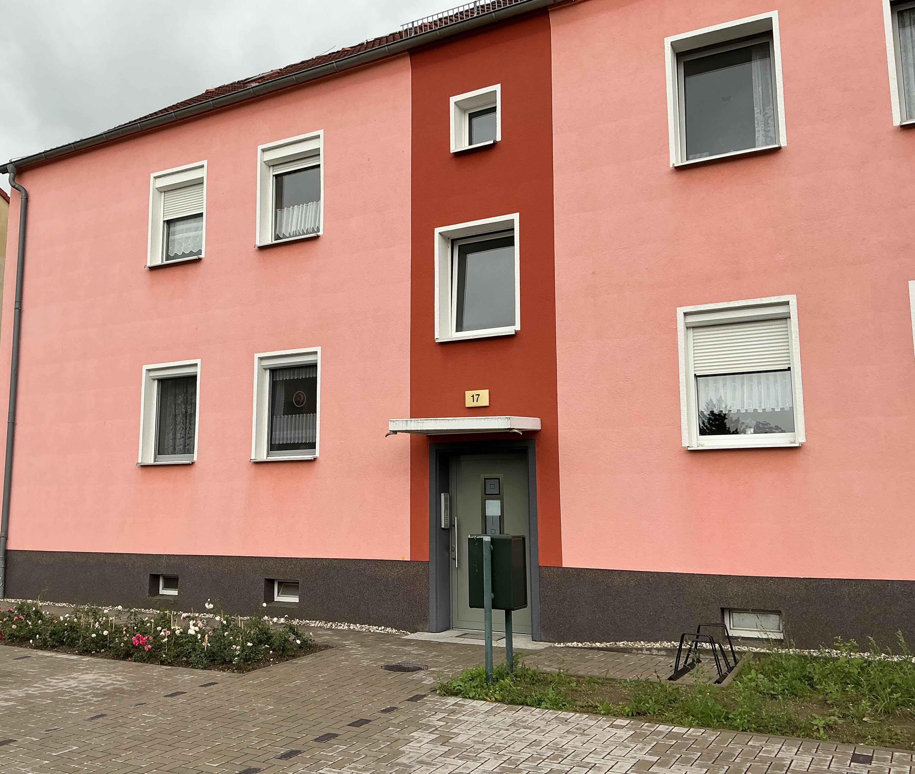 Wohnhaus mit rosa und roter Fassade, Eingangsbereich und Vorgarten